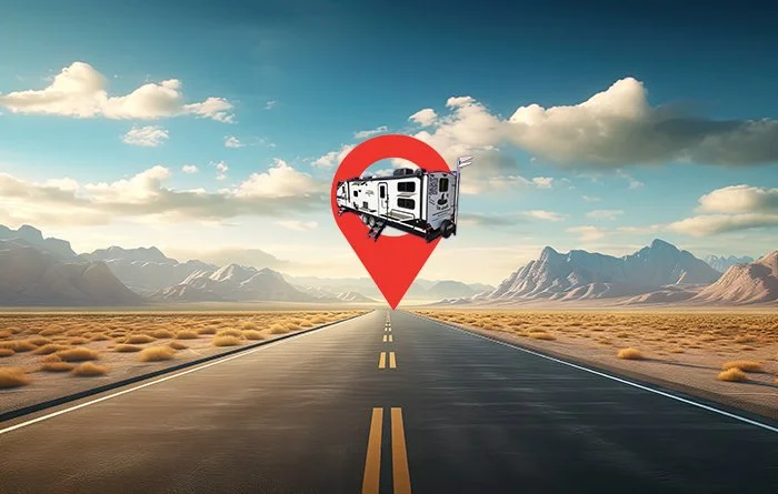 A digital illustration of an empty desert highway leading to distant mountains under a partly cloudy sky, with a large red location pin marker containing a travel trailer on top.