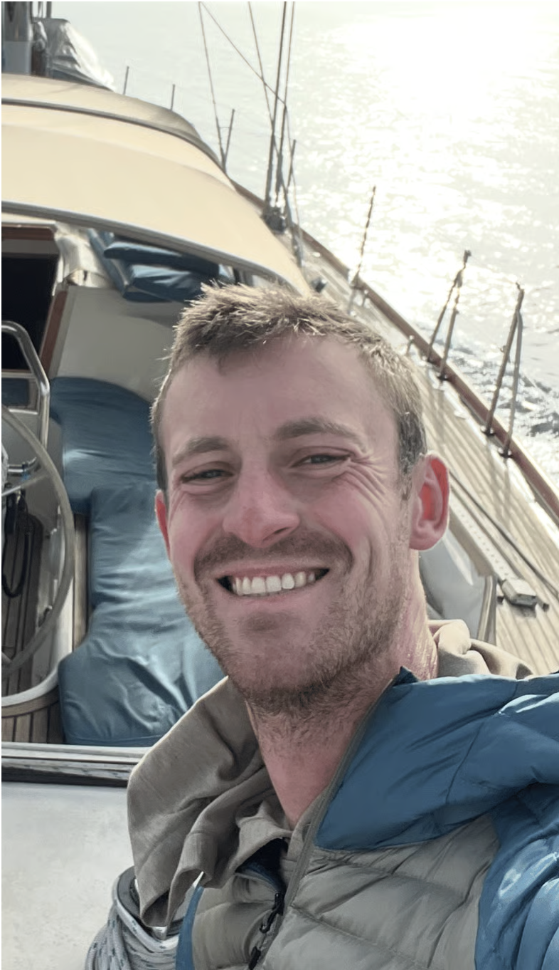 Man taking a selfie on a boat, with water visible in the background.