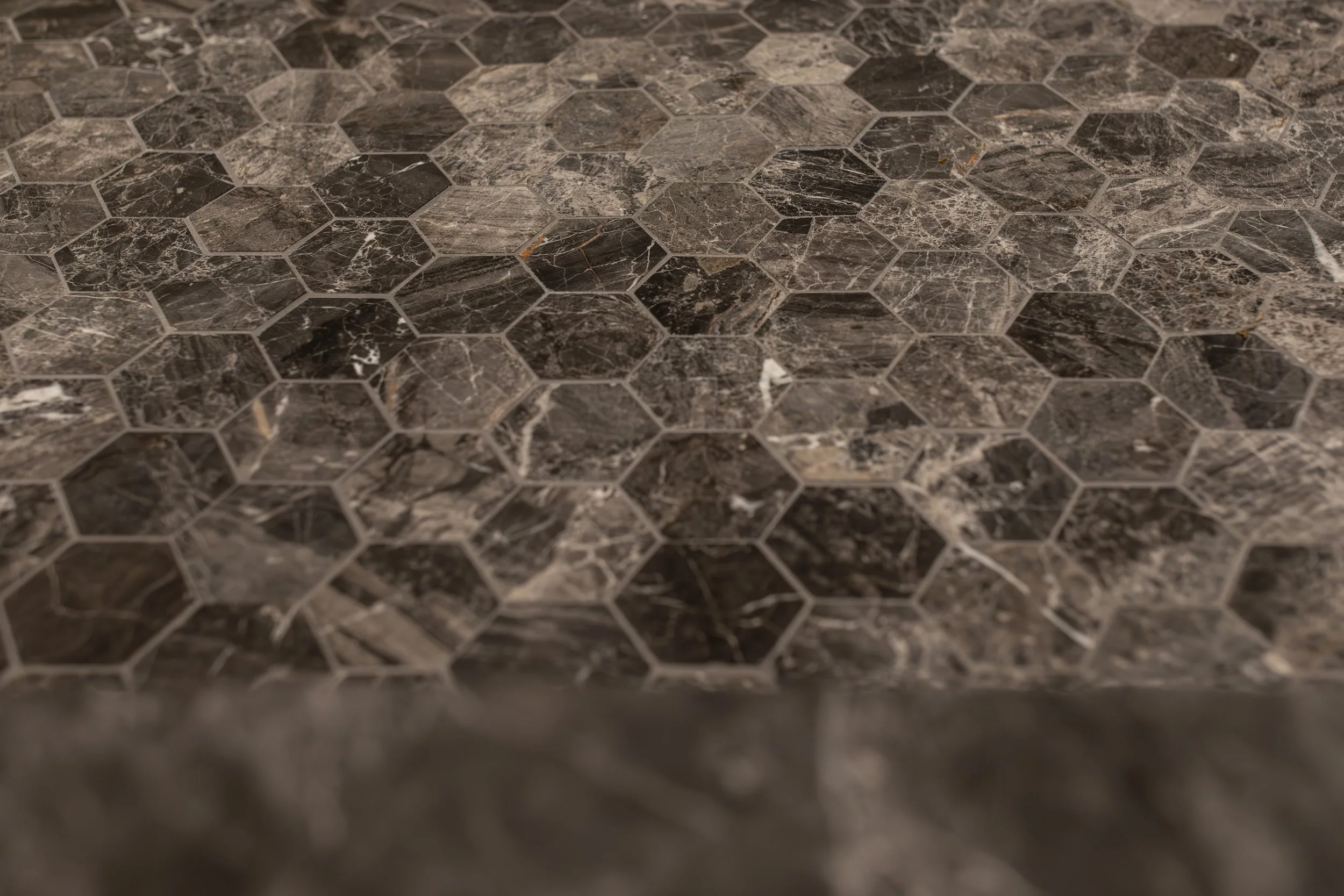 Close-up of a dark brown and black marble hexagonal tile surface.