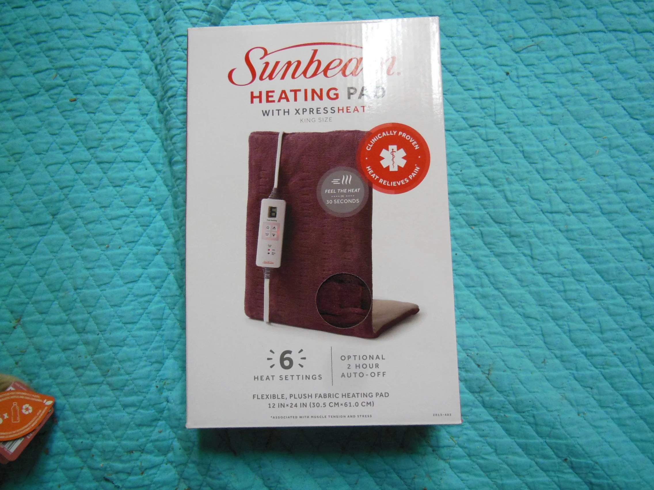 Box for Sunbeam Heating Pad with XpressHeat technology, featuring an image of the burgundy heating pad, a control panel, and highlighted features such as 6 heat settings, optional 2-hour auto-off, and flexible plush fabric.