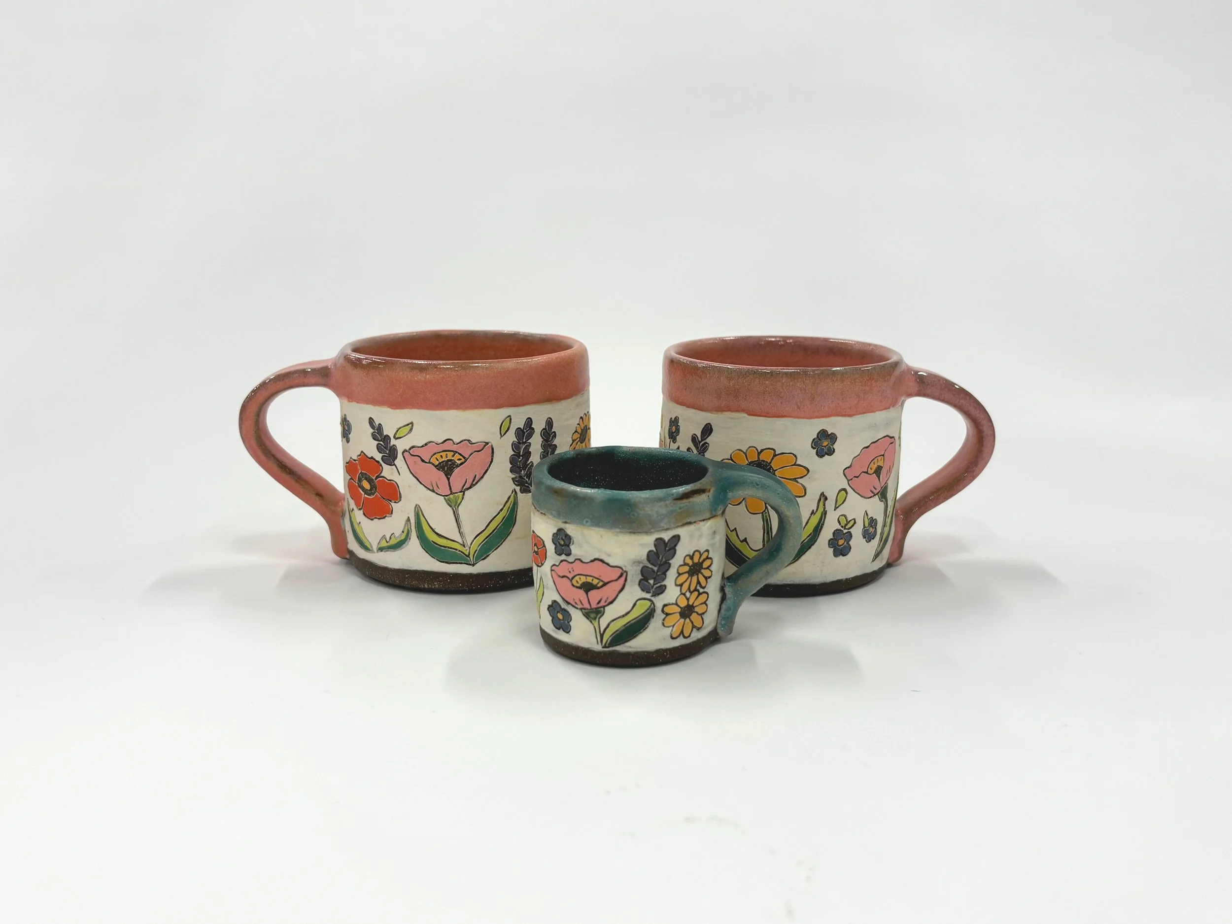 "Wildflower Mugs," 2025, stoneware, slip, underglaze, glaze. Larger mugs: 2 ¾ H x 4 ½ W (with handle) 3 D in.
Smaller mug: 1 7/8  H x 2 7/8 W (with handle) 2 D in. 