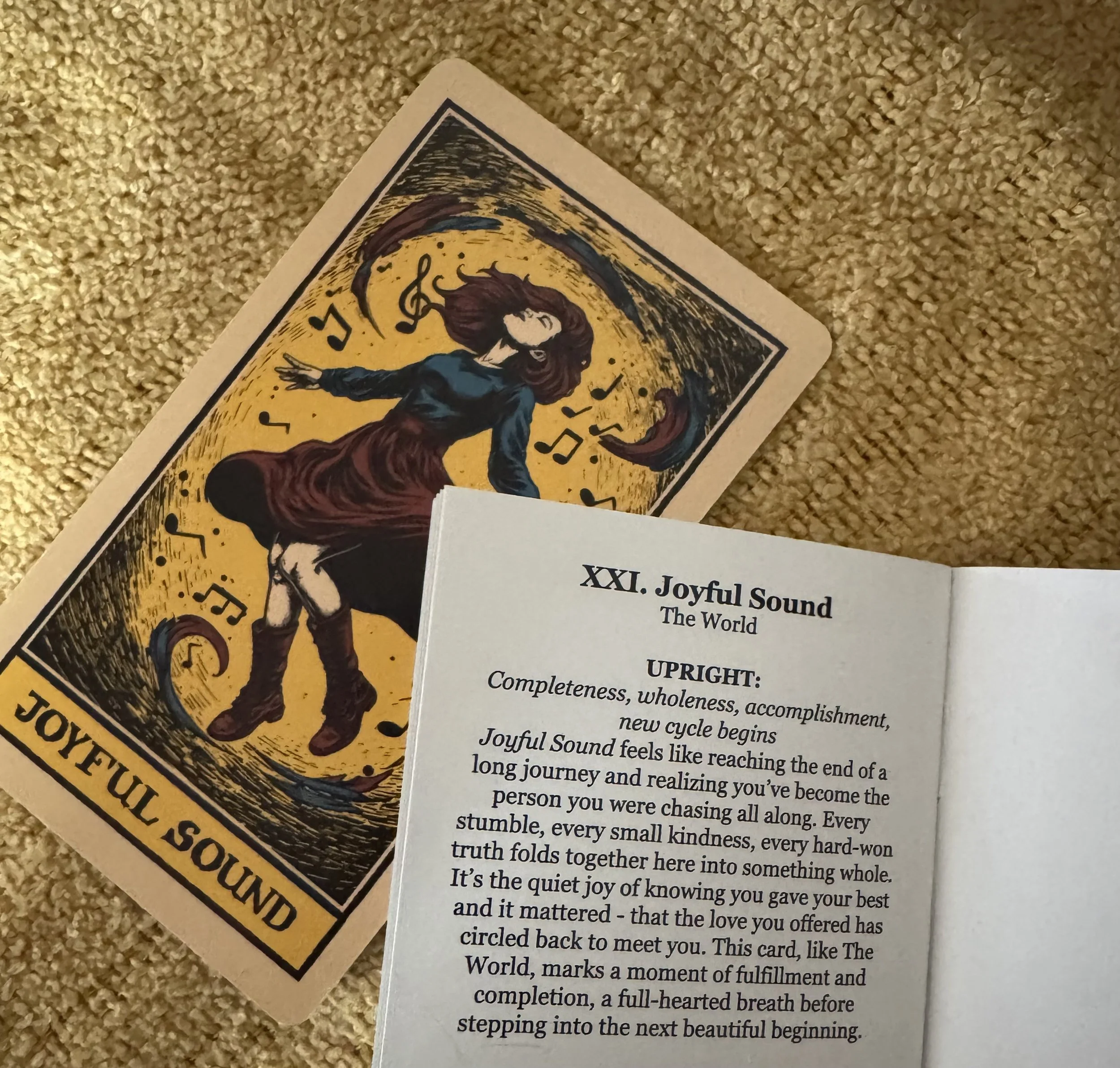 A tarot card titled 'Joyful Sound' depicts a girl dancing with musical notes circling her, set against a yellow and black background, with a poem or message printed on a nearby sheet of paper.