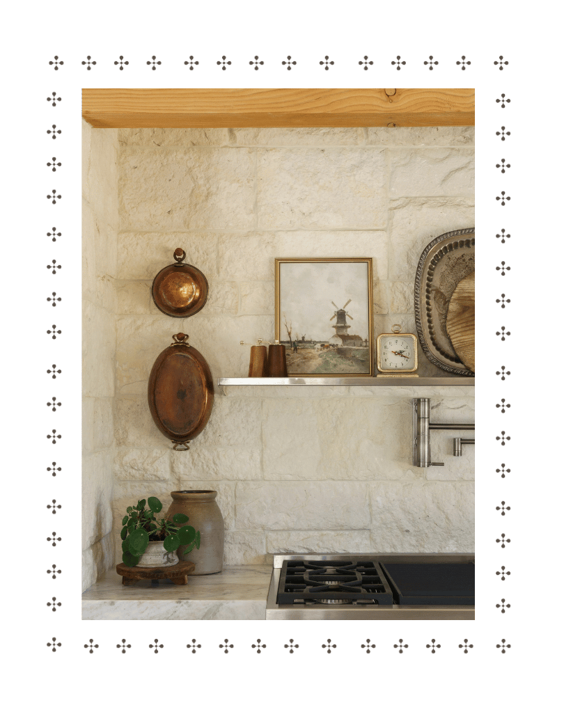 A section of a kitchen with a stone wall, a white shelf holding decorative items, and a part of a stove.