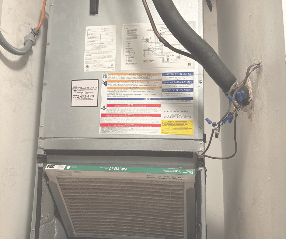 Indoor air conditioning unit installed on a wall with electrical wiring and labels.