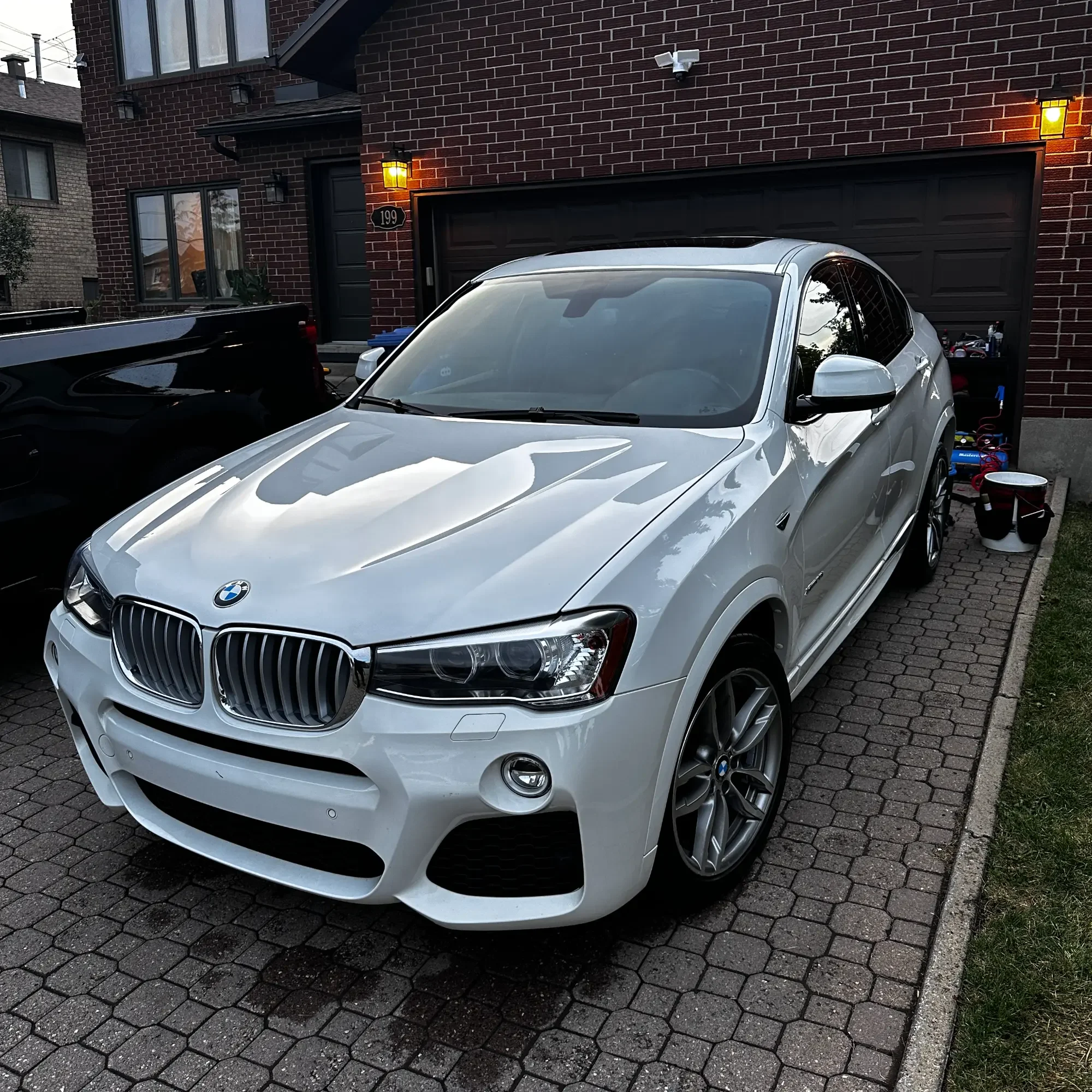 A white BMW SUV parked on a brick driveway