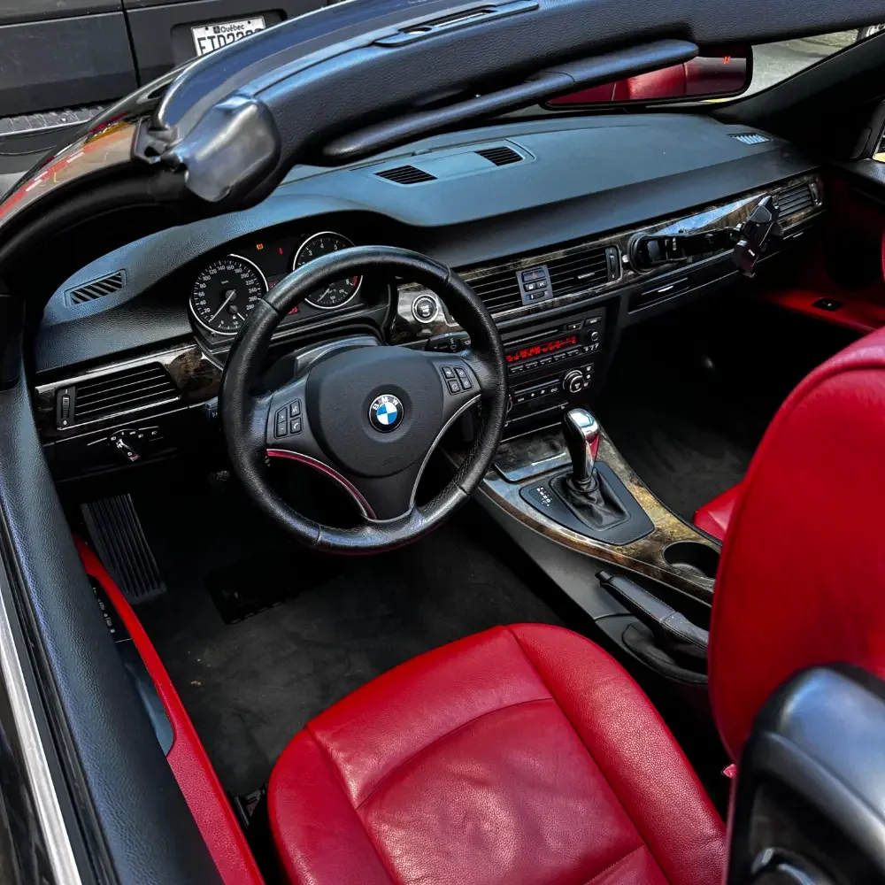 Inside of a BMW car with black dashboard, red leather seats, and a gear shift lever.
