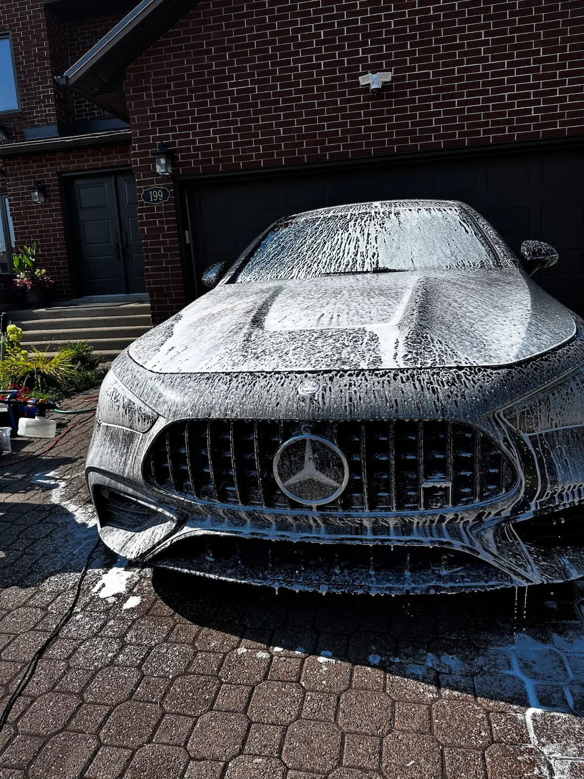 A black Mercedes-Benz car being washed with soap and foam