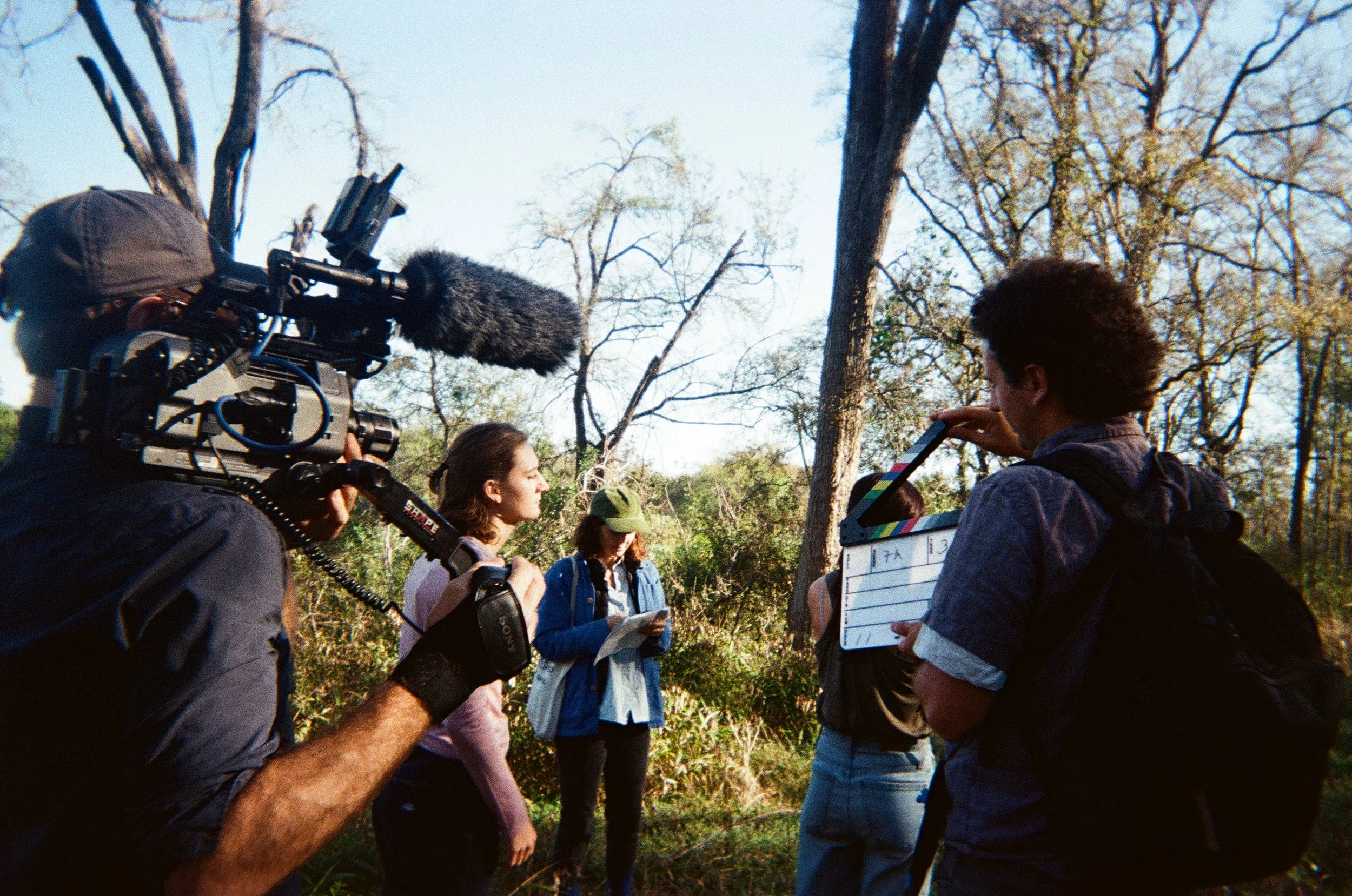 A film crew filming a woman in a forest with trees in the background.