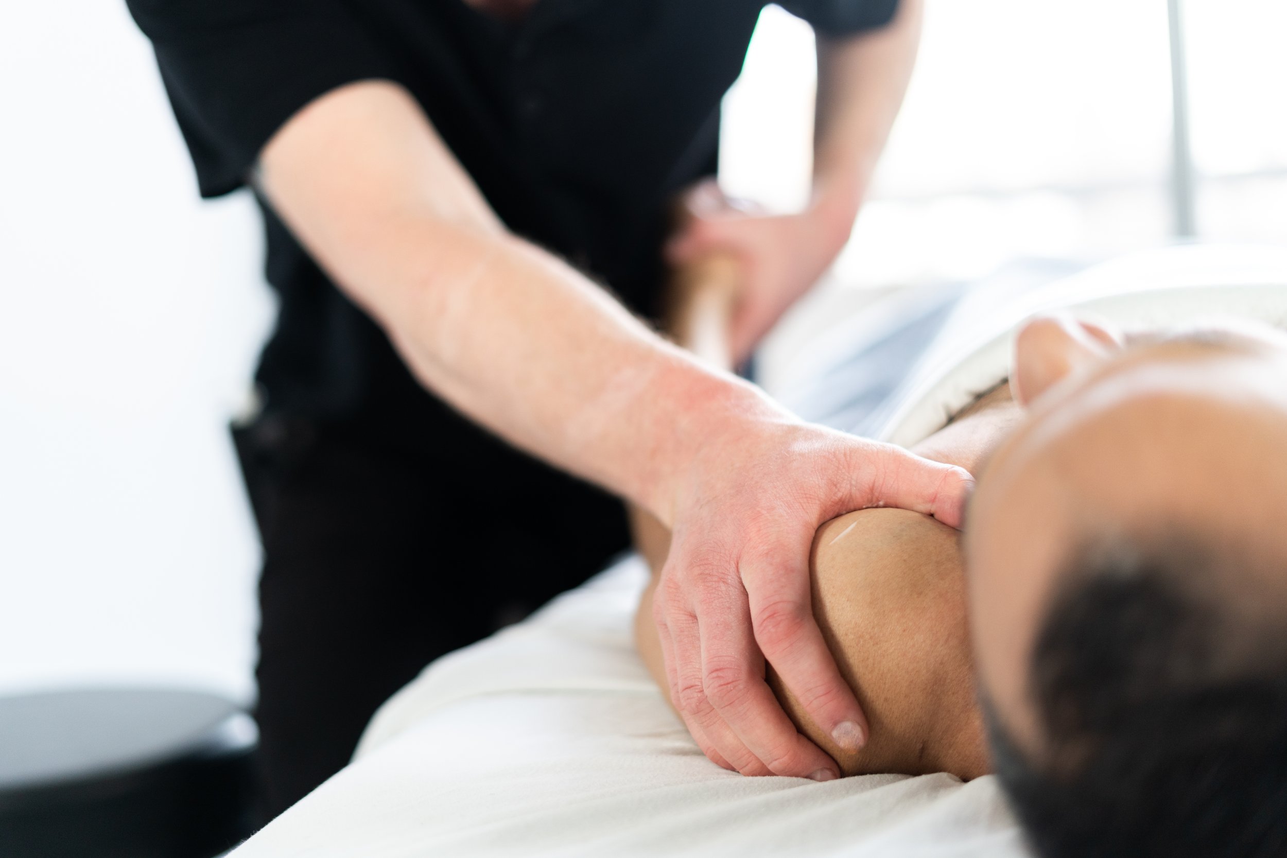David profoarming shoulder massag to a client laying face up on the massage table