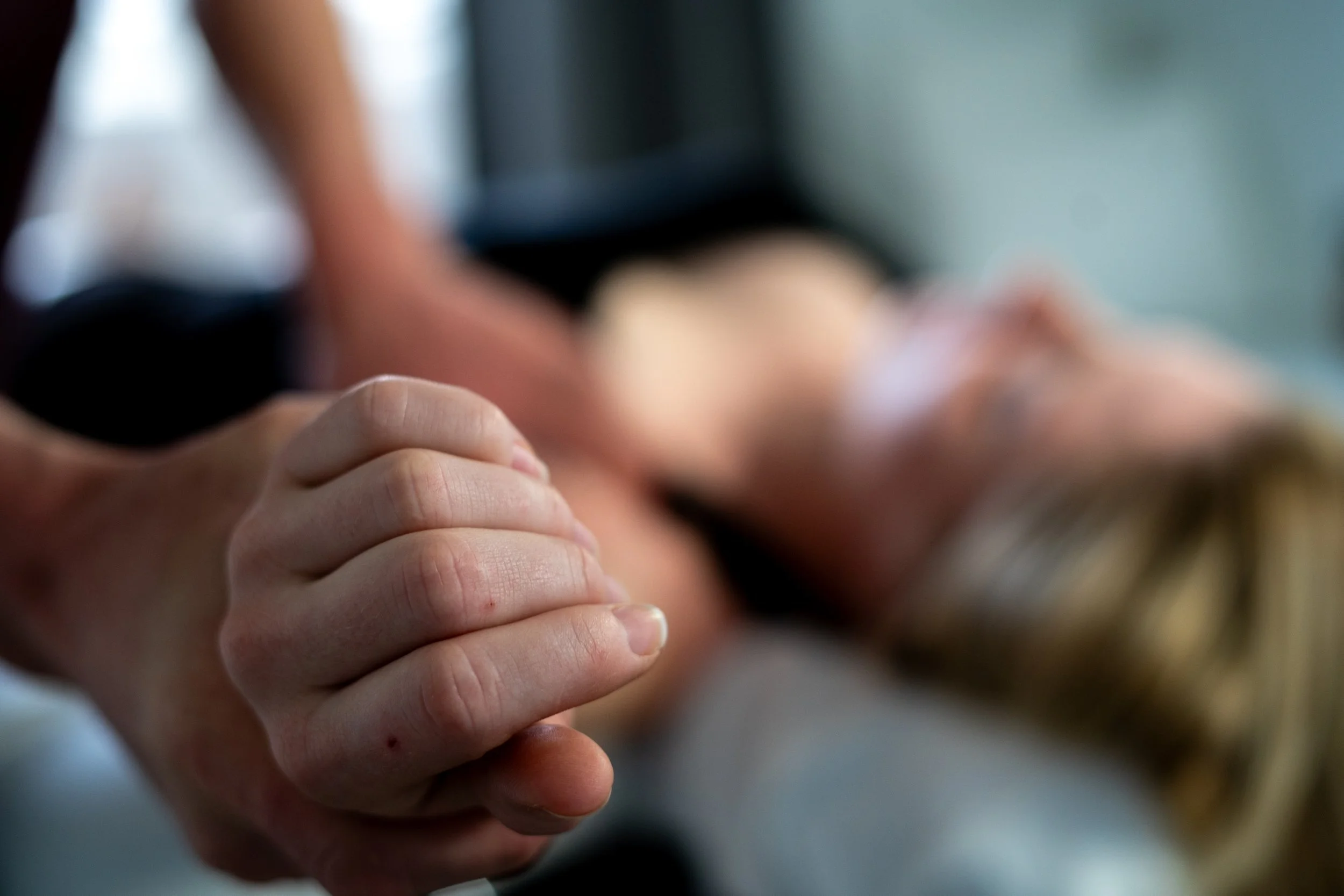Close-up of David performing pec stretching on a woman's arm, focusing on the person's clasped hand