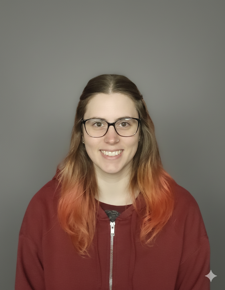 A young woman with glasses, shoulder-length reddish-brown hair, and light skin, smiling against a plain gray background.