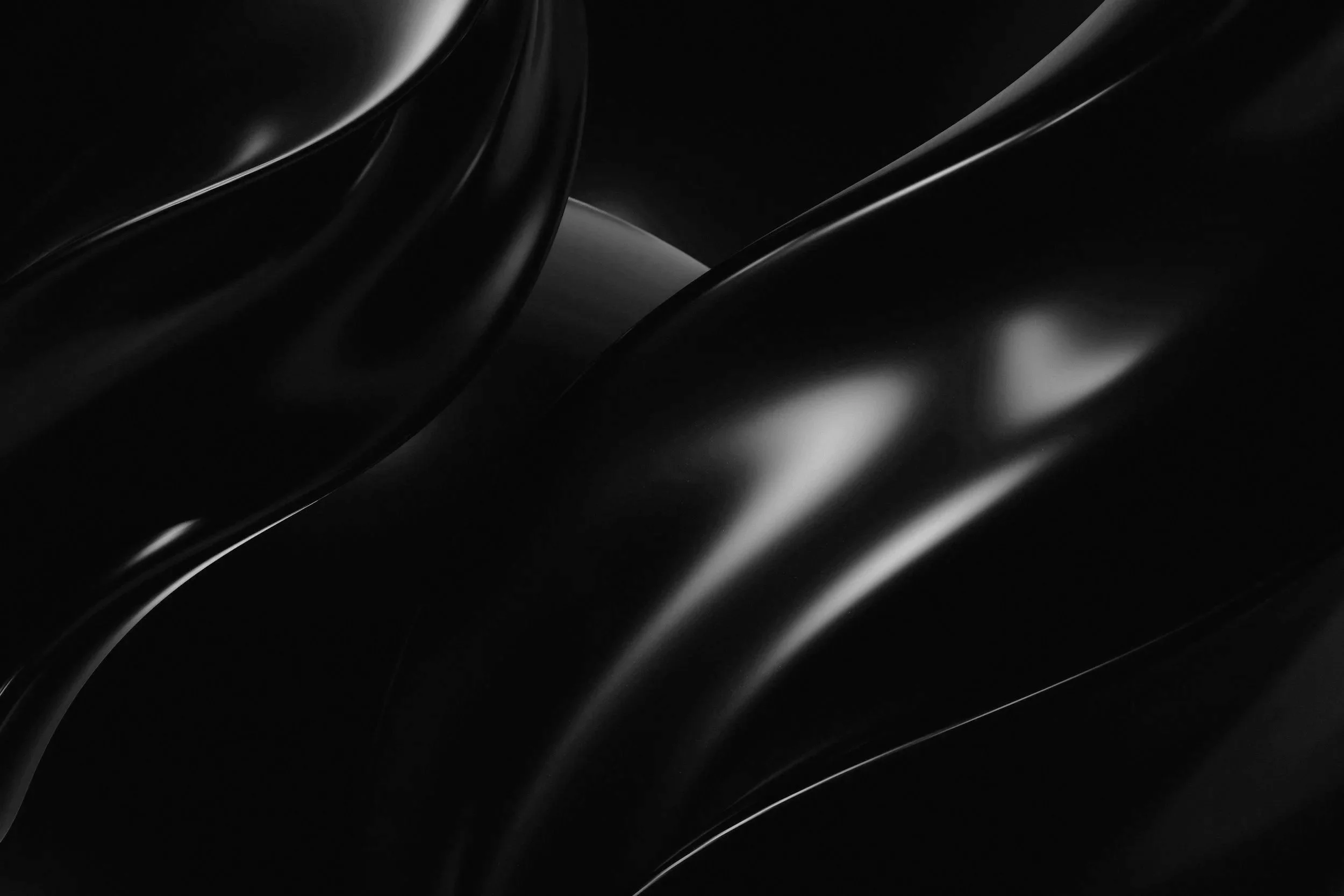 Close-up of black, shiny, curved surfaces with light reflections.