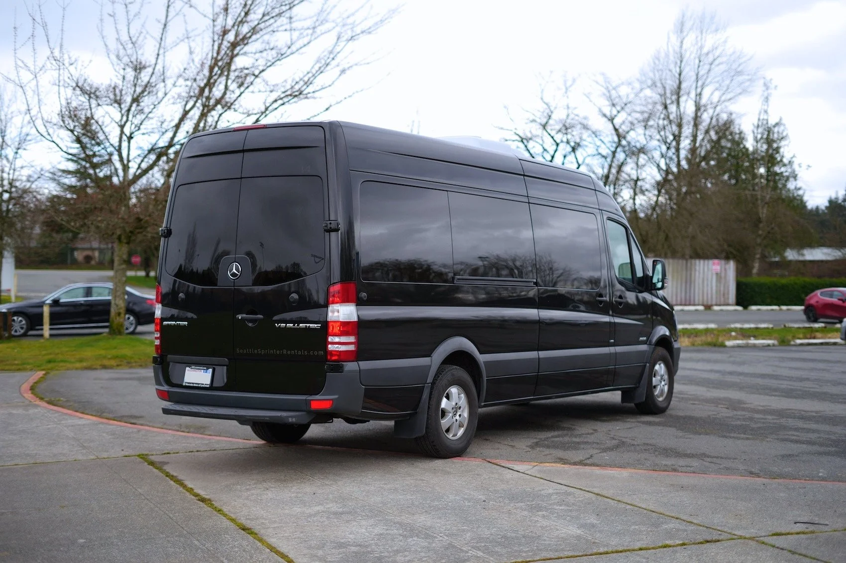 Black Mercedes-Benz Sprinter cargo van parked in a parking lot on a cloudy day