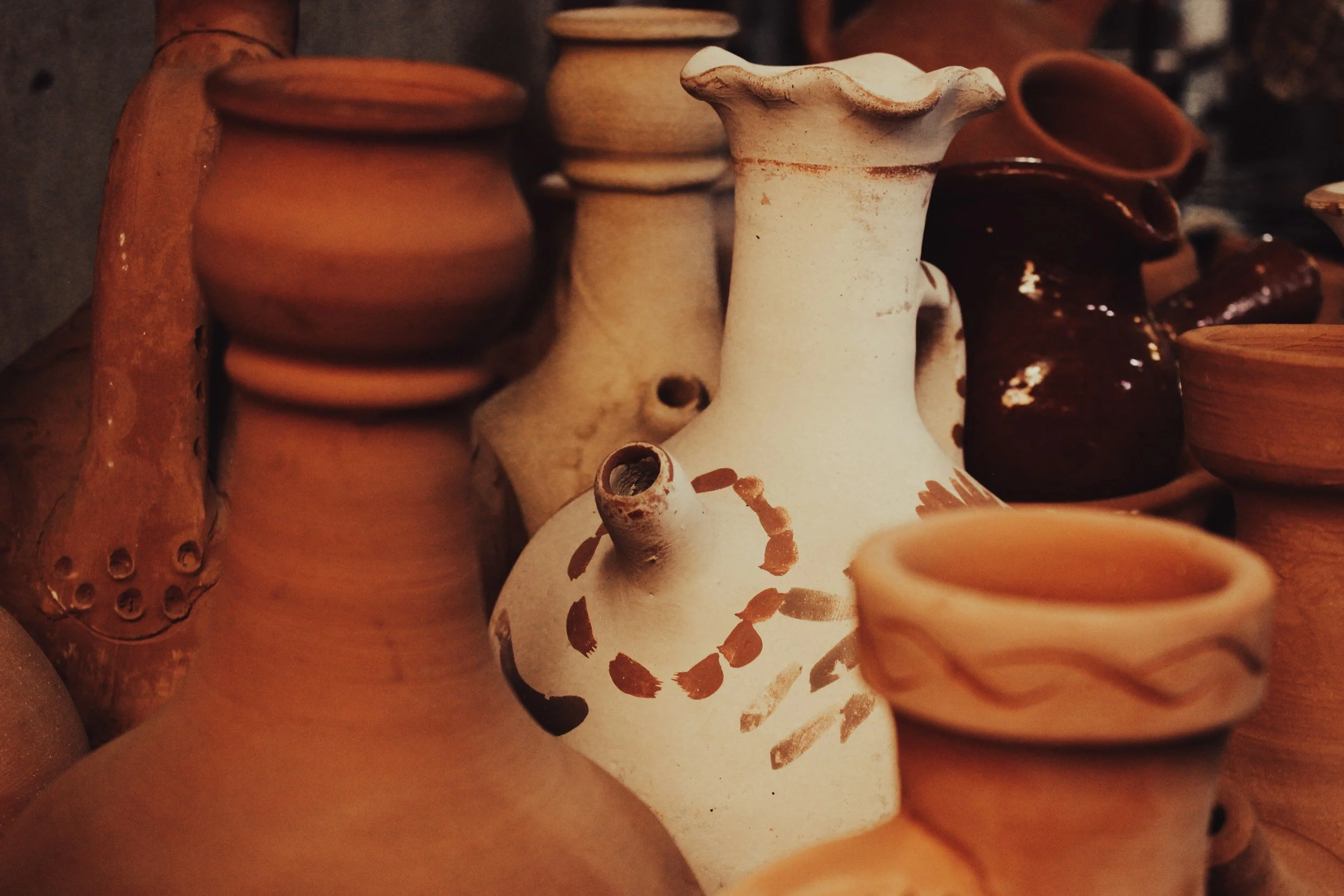 Various handmade ceramic vases and pots in earthy tones, with some featuring painted or textured designs.
