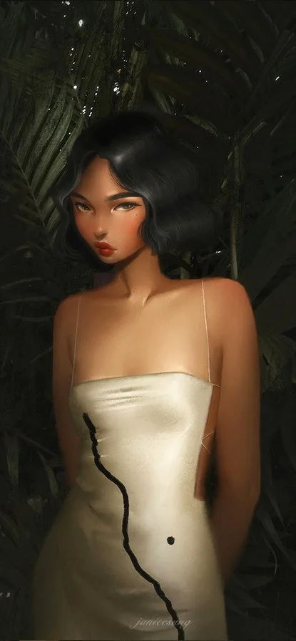 A woman with dark, wavy hair wearing a cream-colored satin dress with thin straps stands in front of lush green tropical foliage.