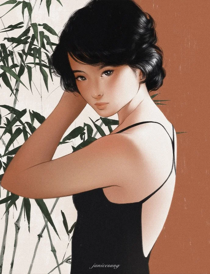 A woman with short black hair in a wavy bob, wearing a black sleeveless dress with thin straps, standing in front of a backdrop with green bamboo leaves and a plain brown wall, looking at the camera.
