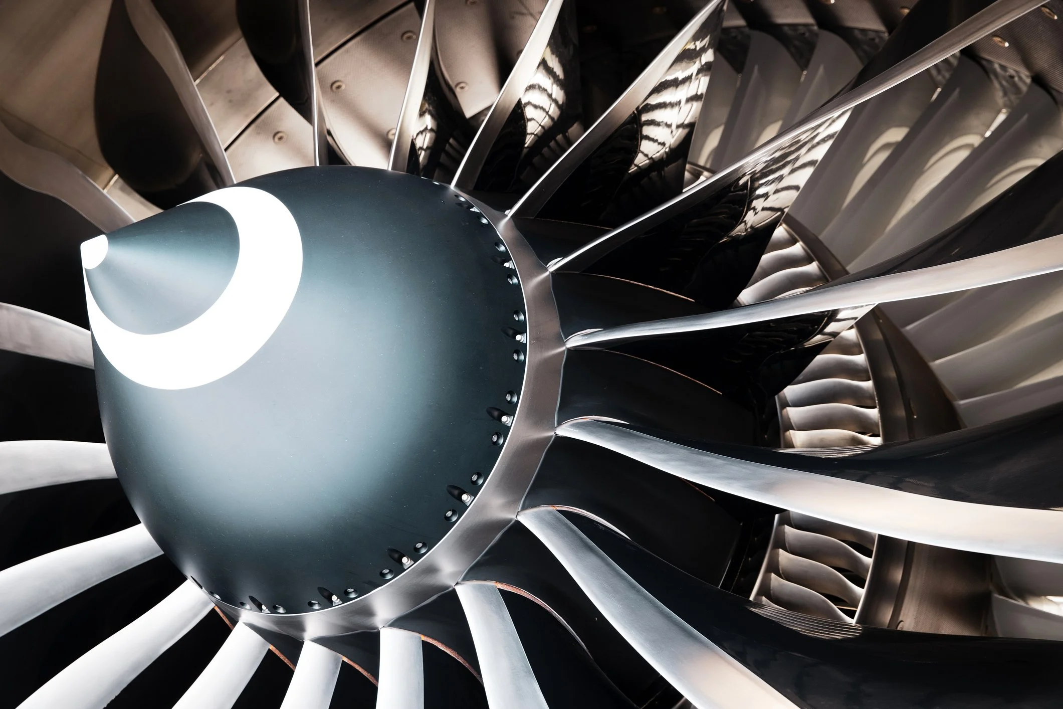 Close-up view of a jet engine's turbine blades and spinner, looking from the front into the engine.
