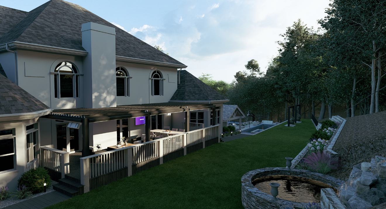 A large white house with a gray shingled roof and multiple windows, featuring an outdoor patio area with tables and chairs, surrounded by a well-maintained grassy yard, trees, and a stone fountain in the foreground.