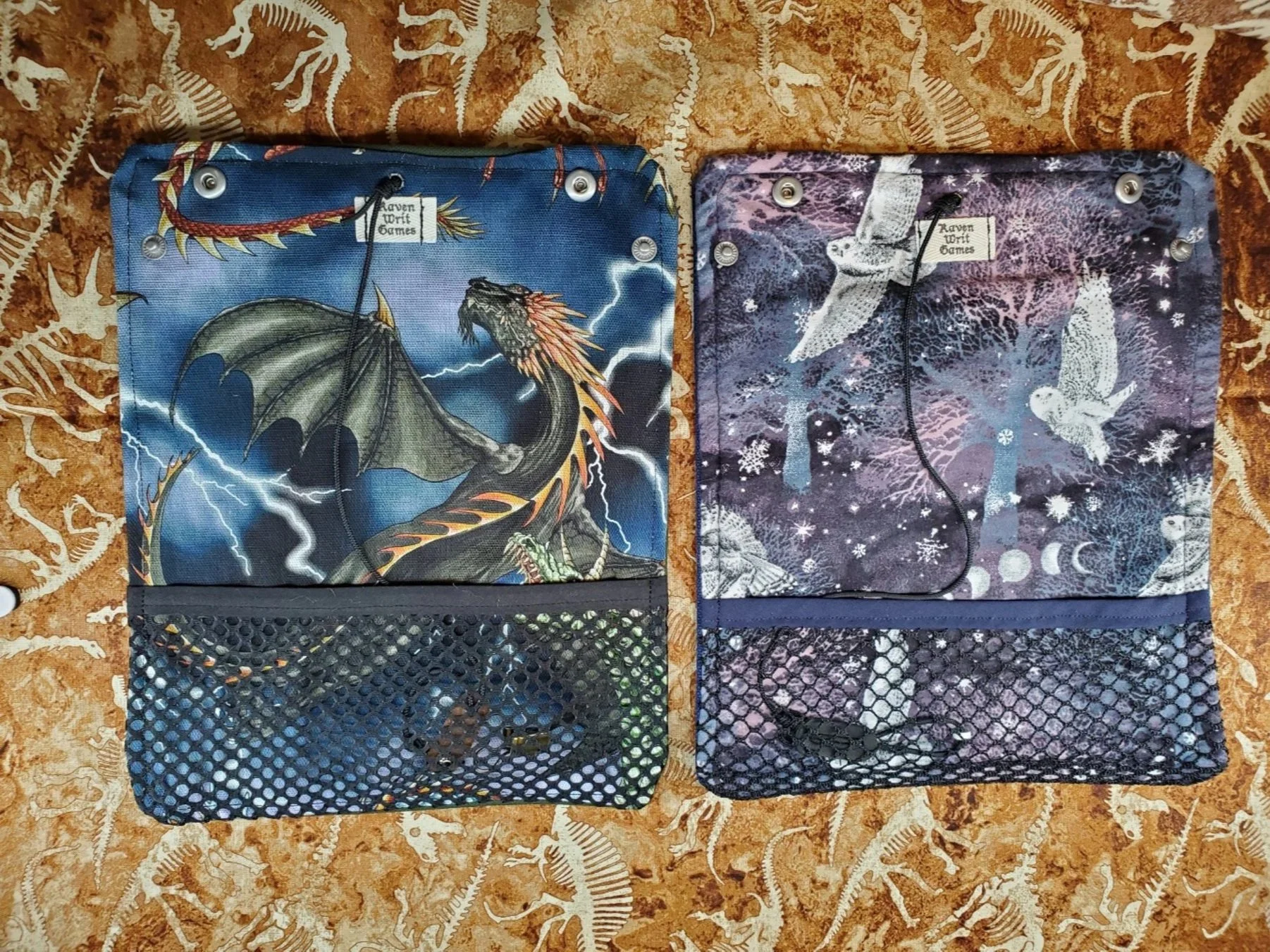 2 canvas and cotton print Dice Rolls. One with dragons and the other with snowy owls. Each feature mesh pockets to hold dice.