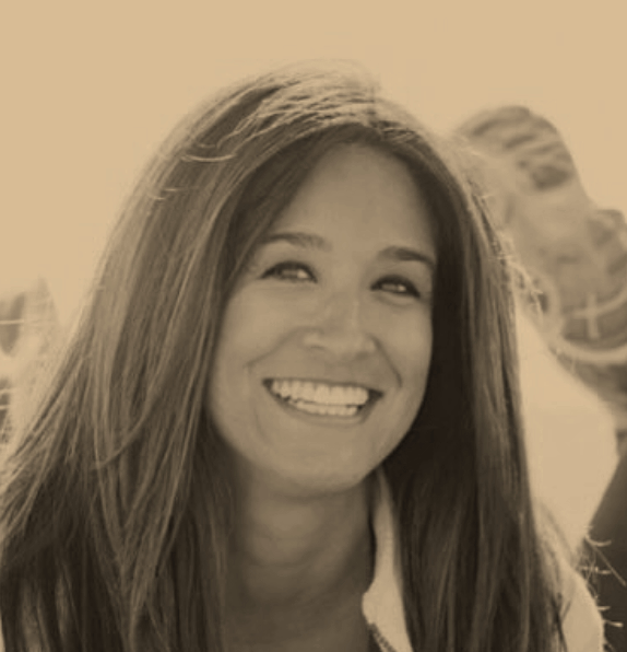 Smiling woman with long hair, outdoors, in sepia tone.