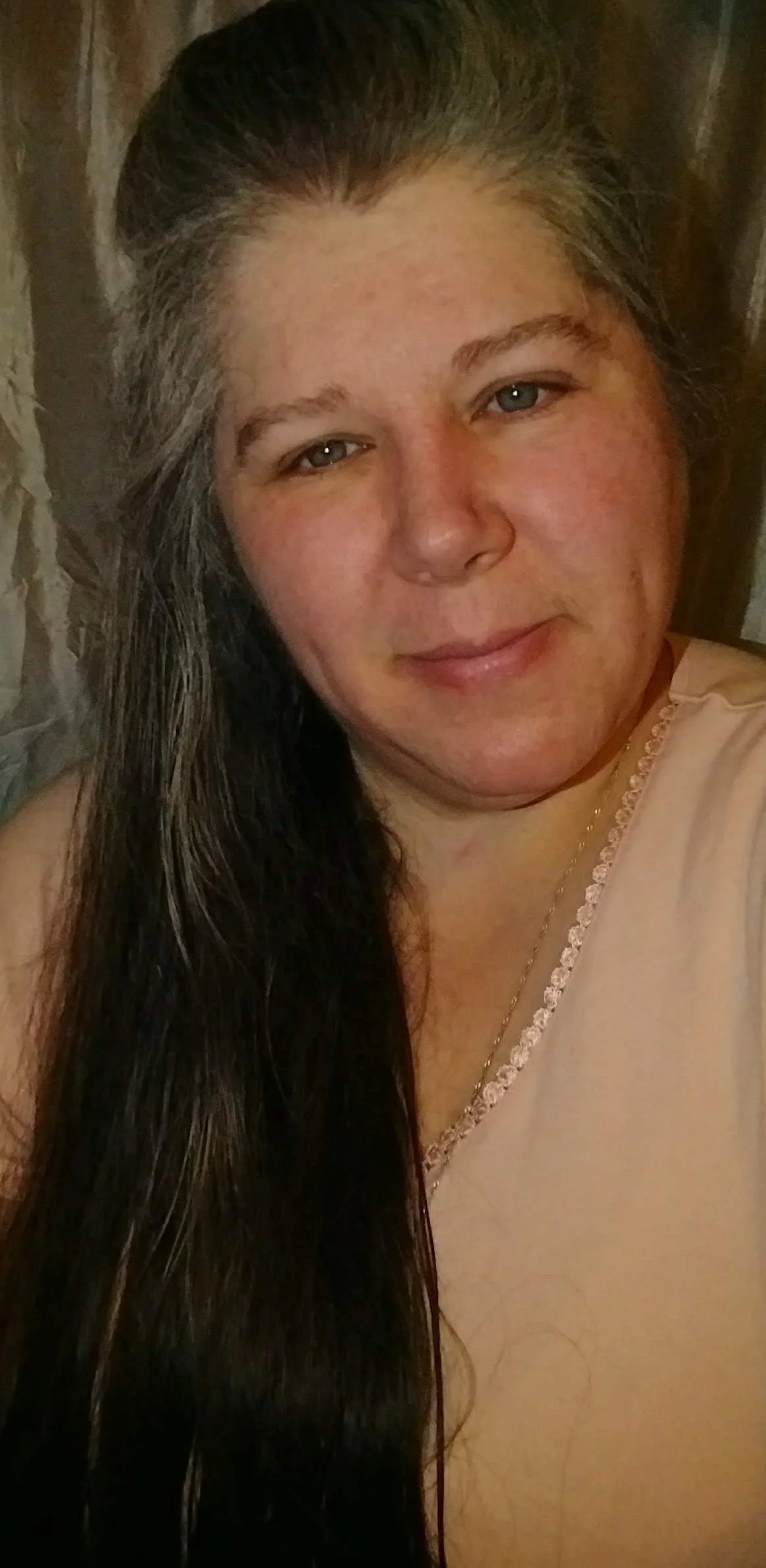 Author Michelle Tringali, with long dark hair, smiling gently, standing in front of a wooden background.