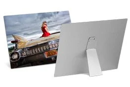 Rear view of a computer monitor showing a picture of a person in a red outfit sitting on a vintage car with a cloudy sky background.