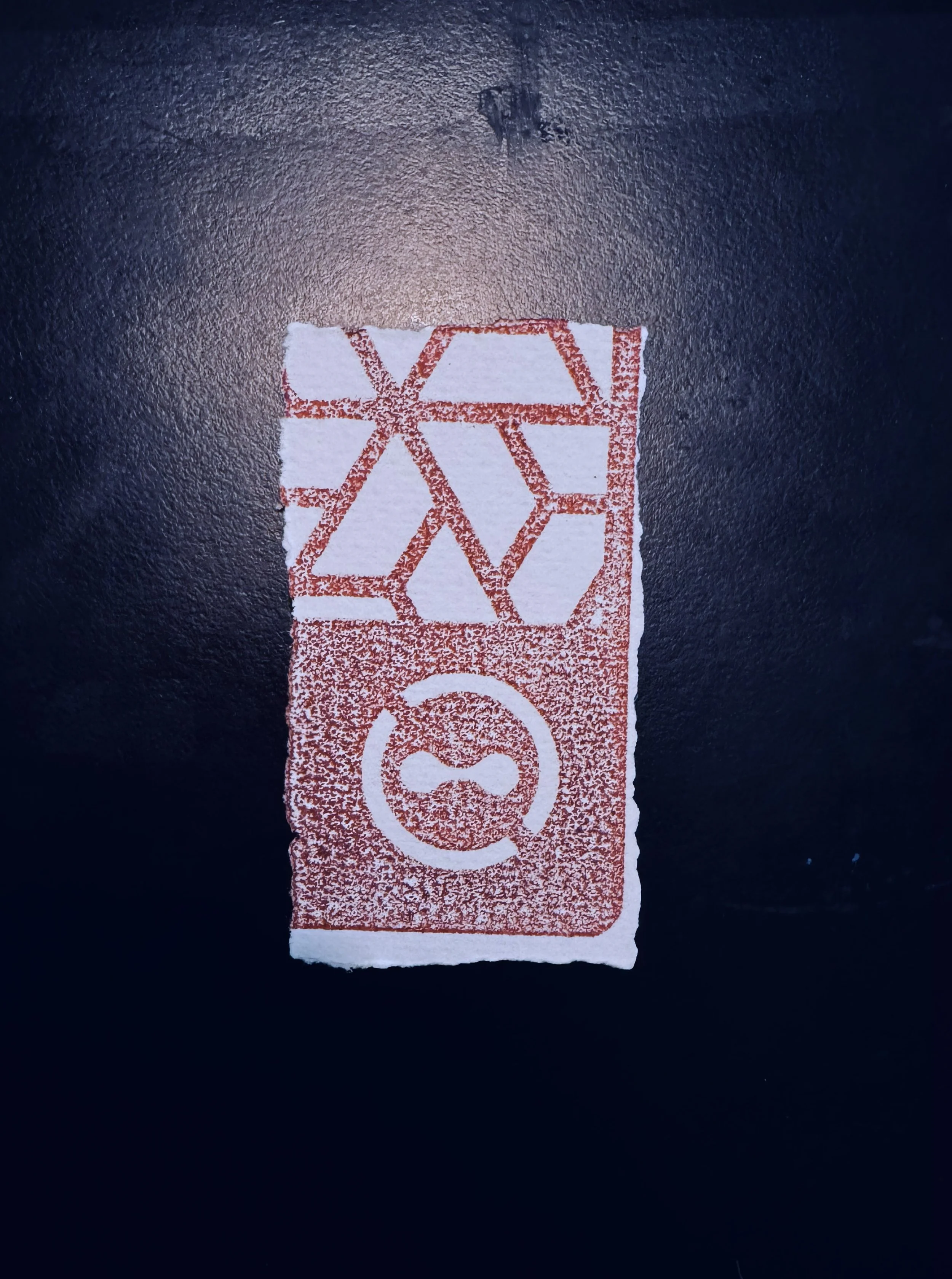 A piece of paper with red printed symbols, including hexagons, circles, and a Wi-Fi signal icon, on a dark surface.