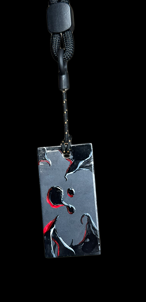 Close-up image of a black mobile phone lanyard with a metal keychain attached, showing a reflective surface with abstract black, white, and red design.