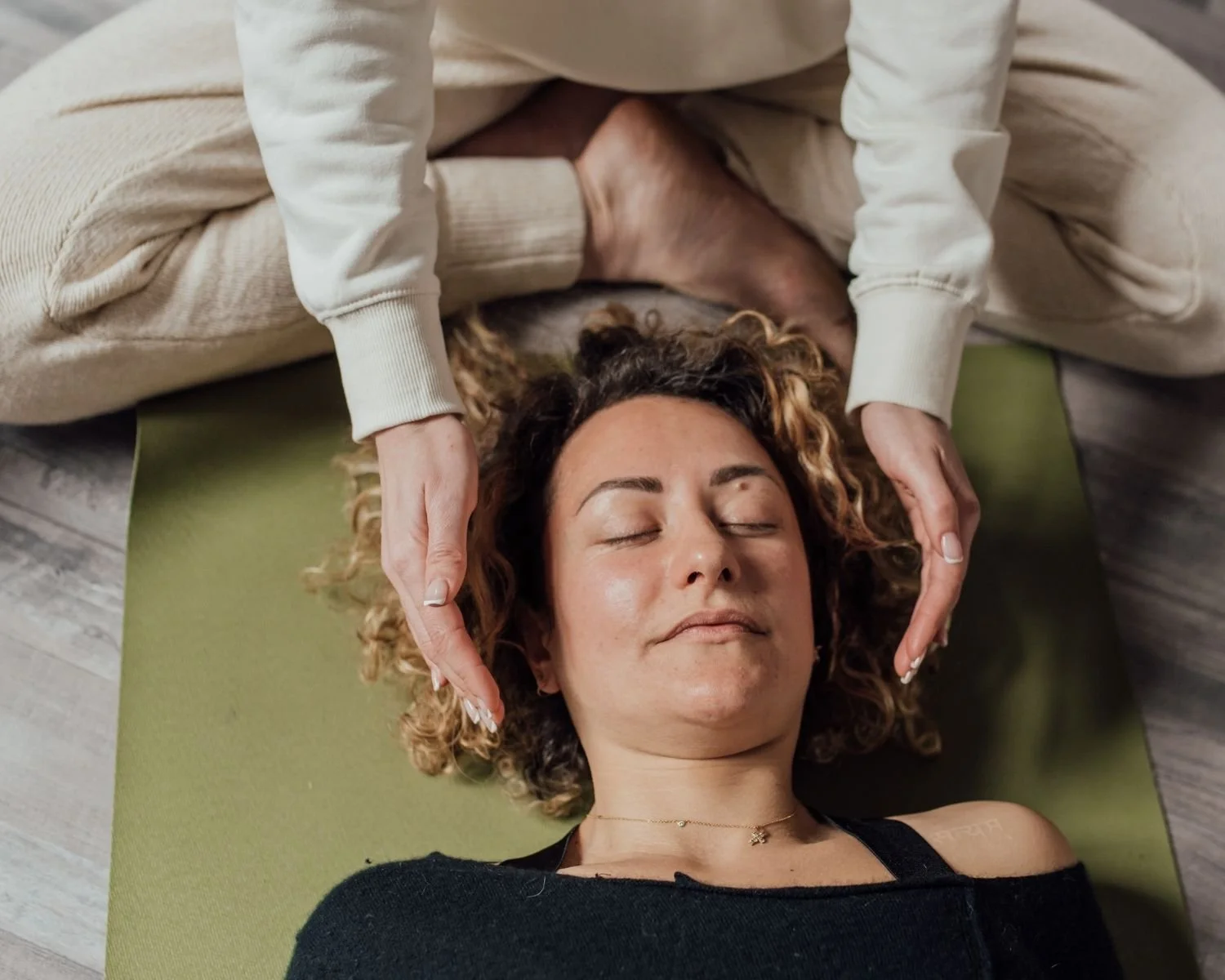 Person receiving a head massage while lying on a yoga mat.