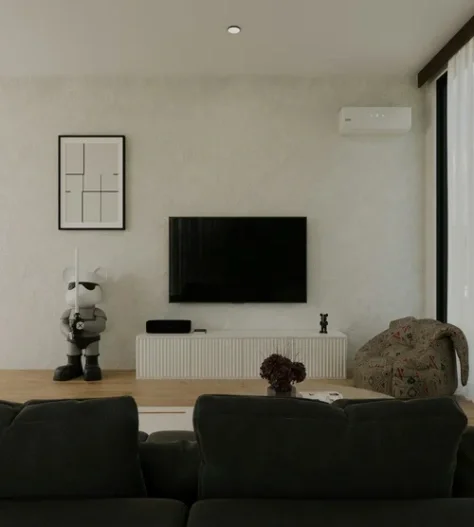 Living room with black sofa chairs, a TV mounted on a textured beige wall, a white table, plant, artwork, decorative items, a wall-mounted air conditioning unit, a patterned armchair, and large window with white curtains.