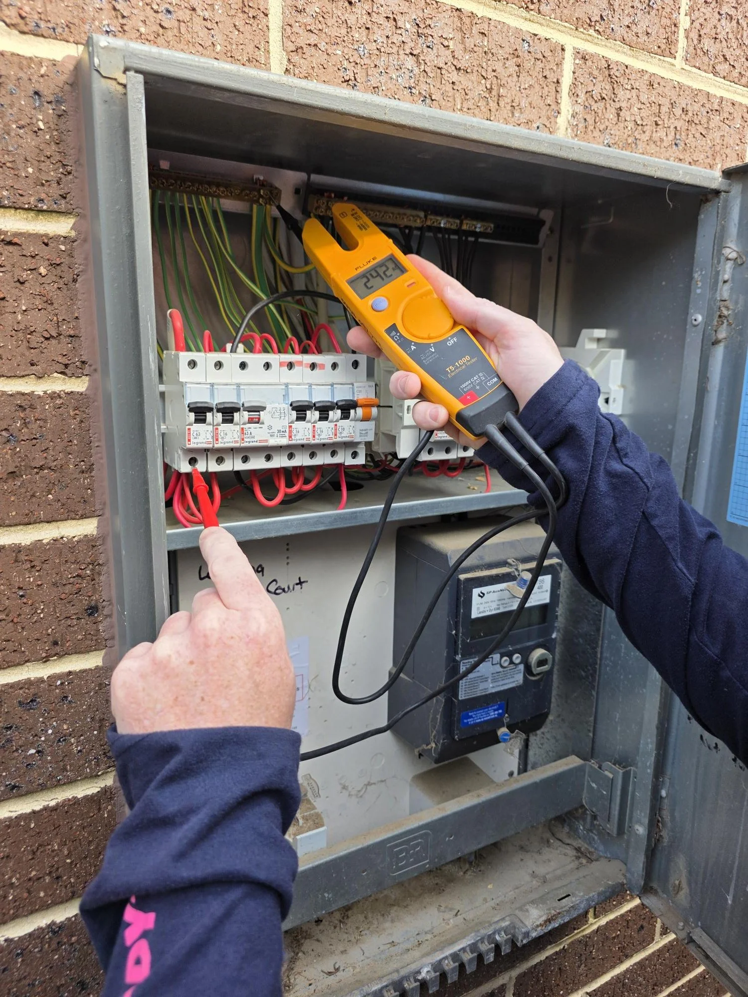 Electrician testing an electrical panel with a digital multimeter.