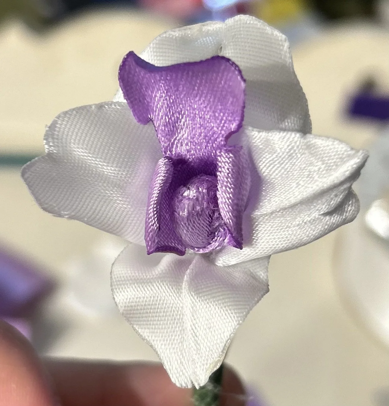 Close-up of a fabric flower in purple and white.