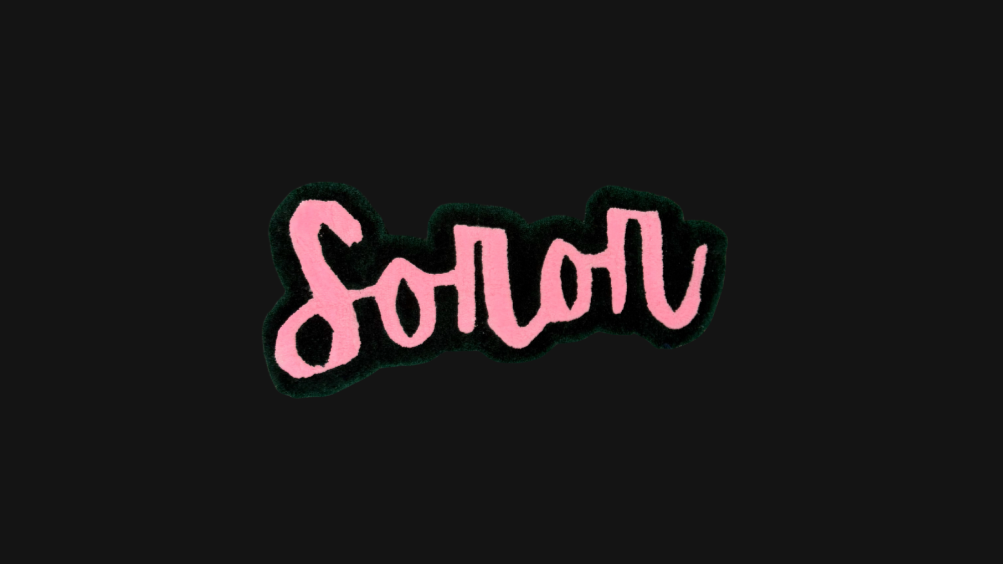 Pink and Green rug with the word "Soror" on a black background.
