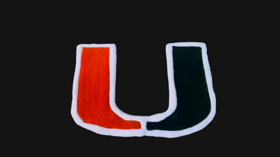 Colorful rug of the University of Miami logo with orange, green, and white on black background.