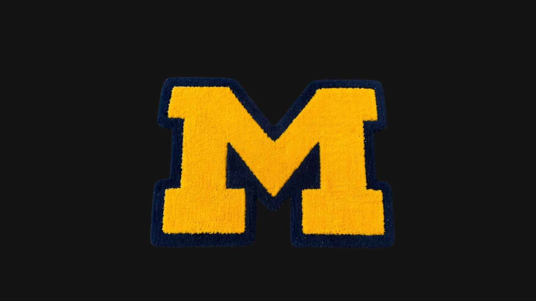 A 24 inch rug of the University of Michigan 'M' logo, on a black background.
