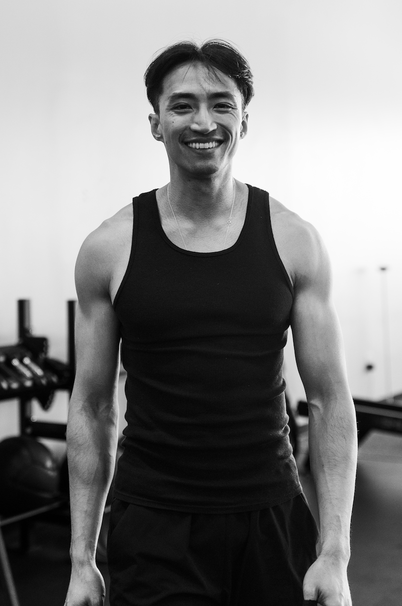 Frank Chen fitness coach standing in a gym focused on building strength and confidence through training