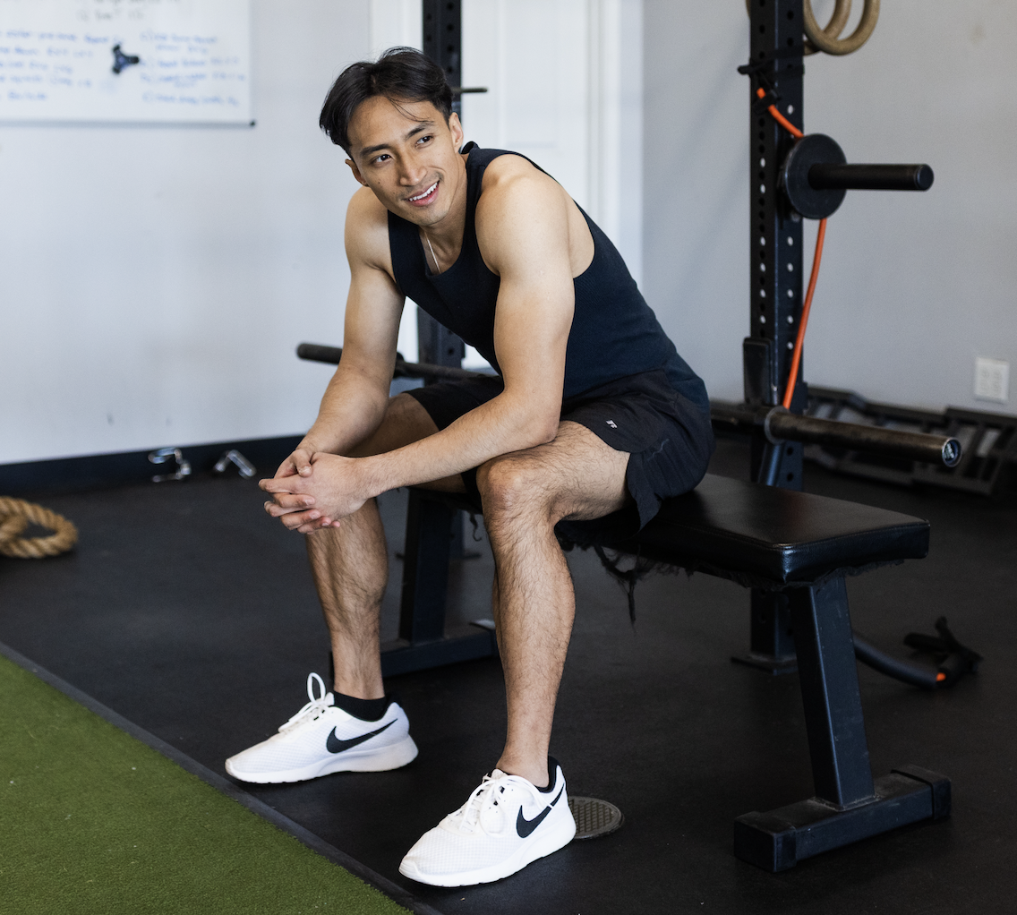 Frank Chen fitness coach resting between sets in a gym during a strength training workout