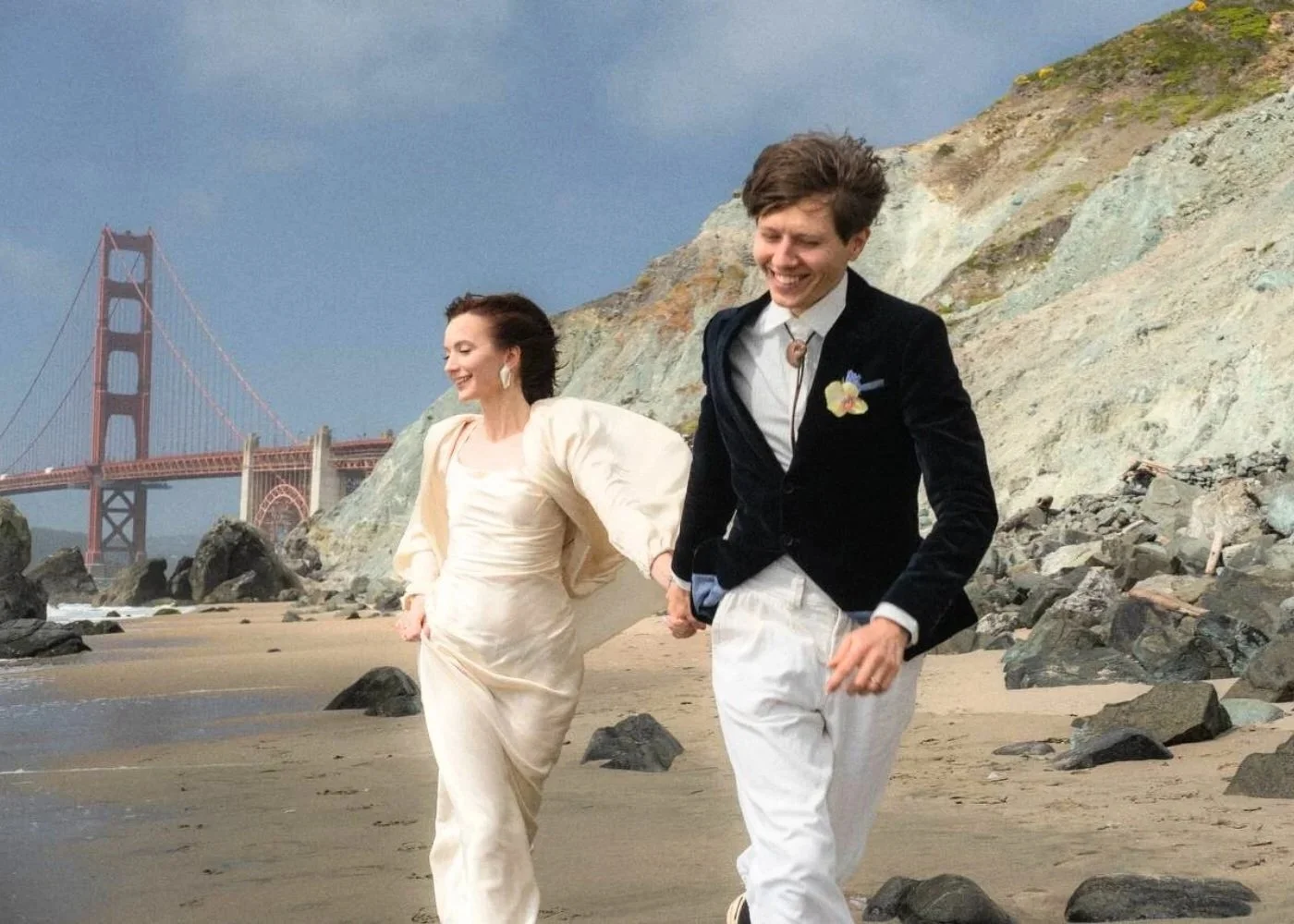 Bride and groom running on a beach with the Golden Gate Bridge in the background