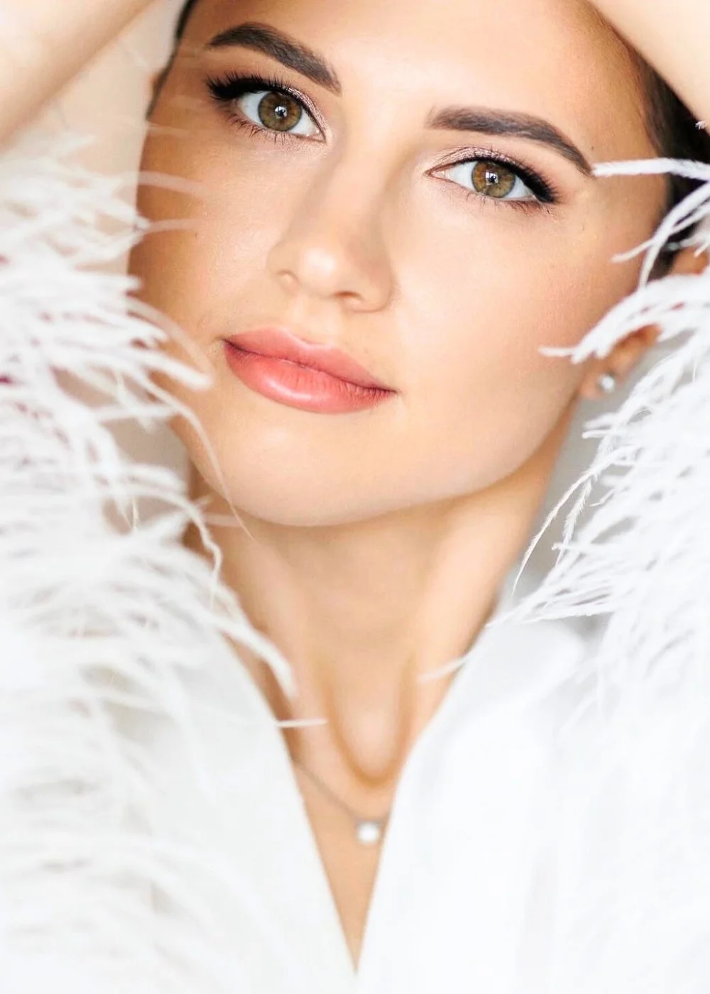 Soft bridal beauty close-up with natural glam makeup and white feather details