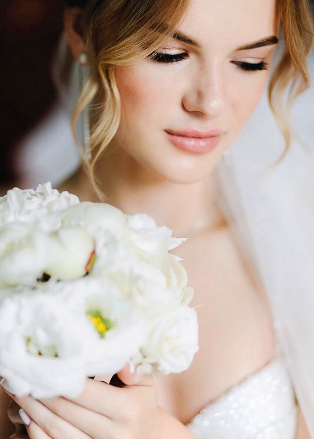 Bride holding a bouquet with natural bridal makeup and a soft updo