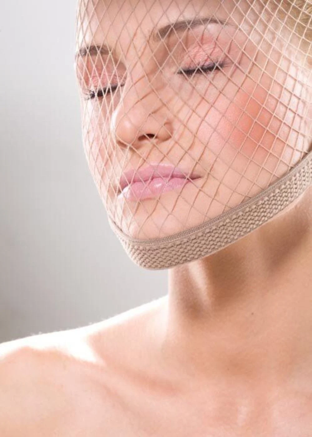 Beauty portrait with birdcage veil and soft bridal makeup, closed eyes