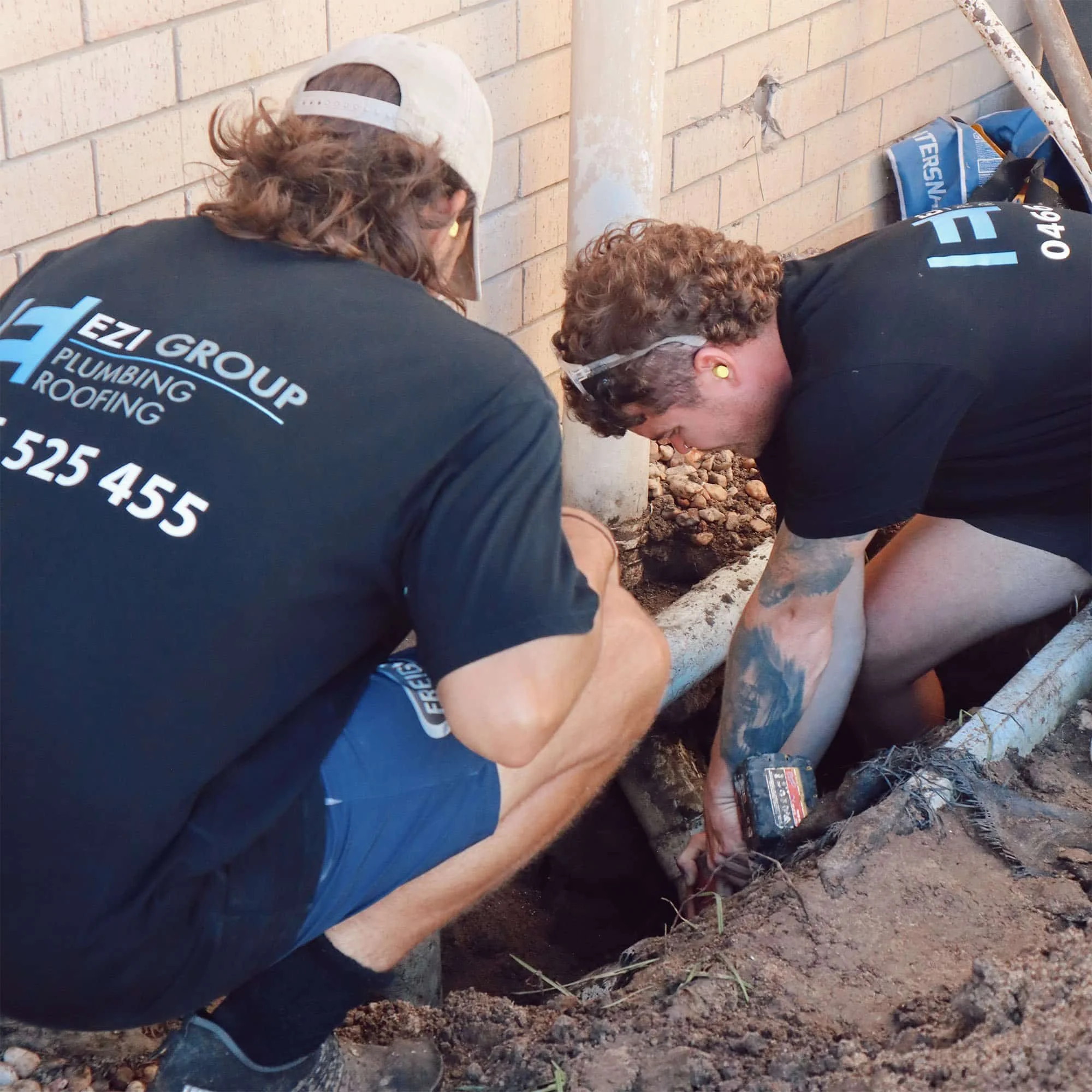 A photo of Ezi Group's Michael and an apprentice working on a customer's drainage issue.
