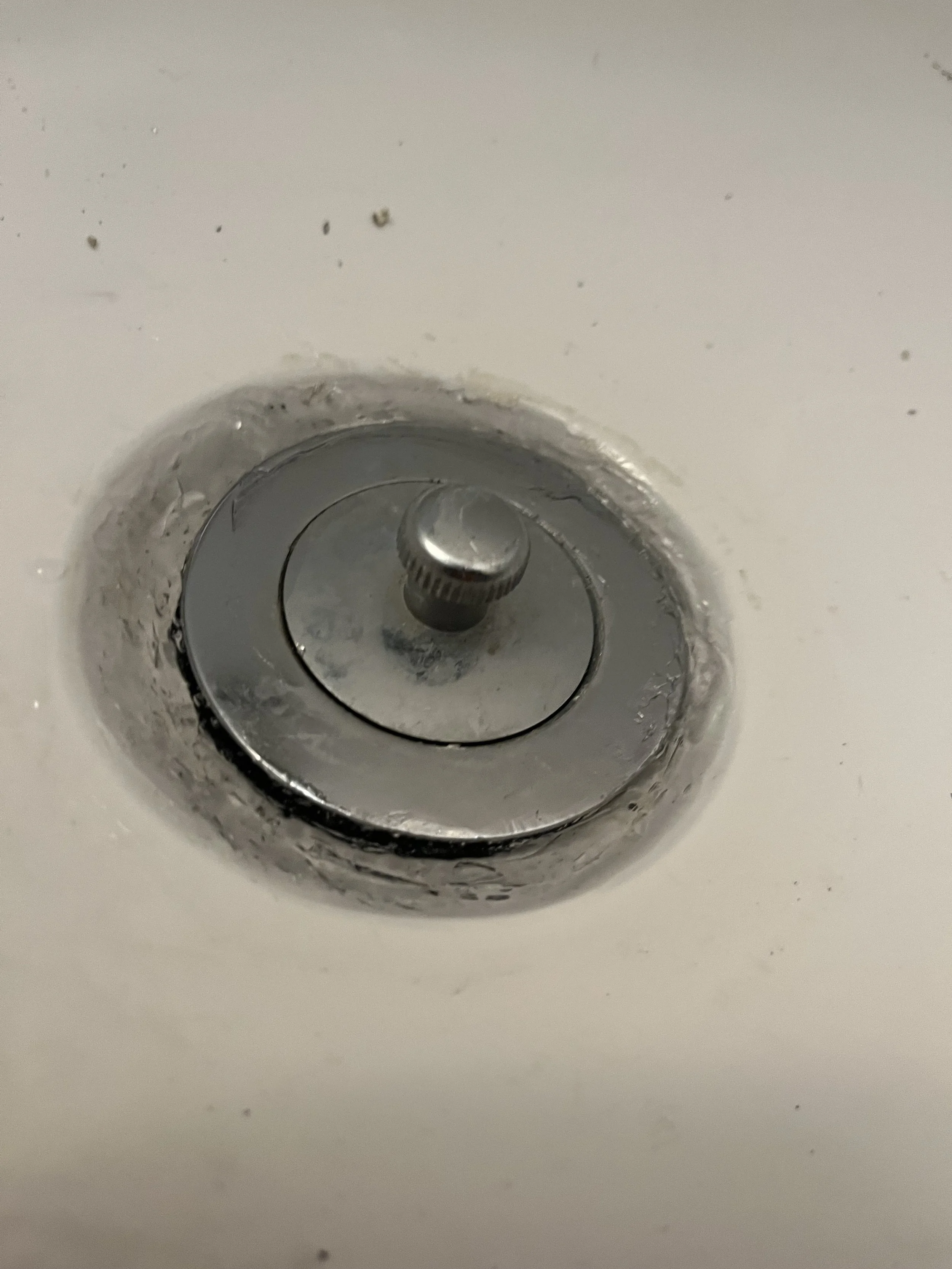 Close-up of a drain with a metal stopper 