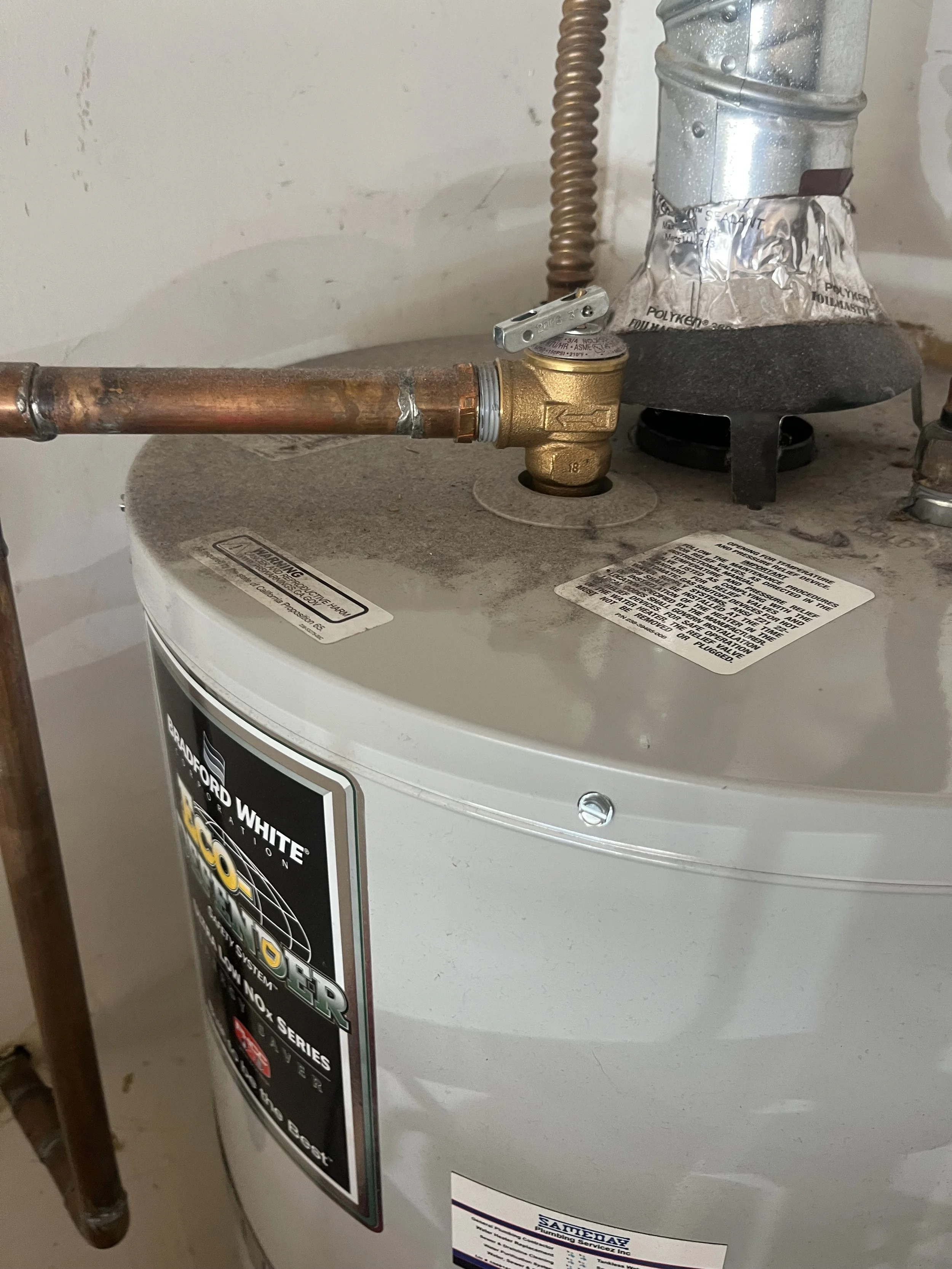 Close-up of a water heater with copper pipes and a pressure valve