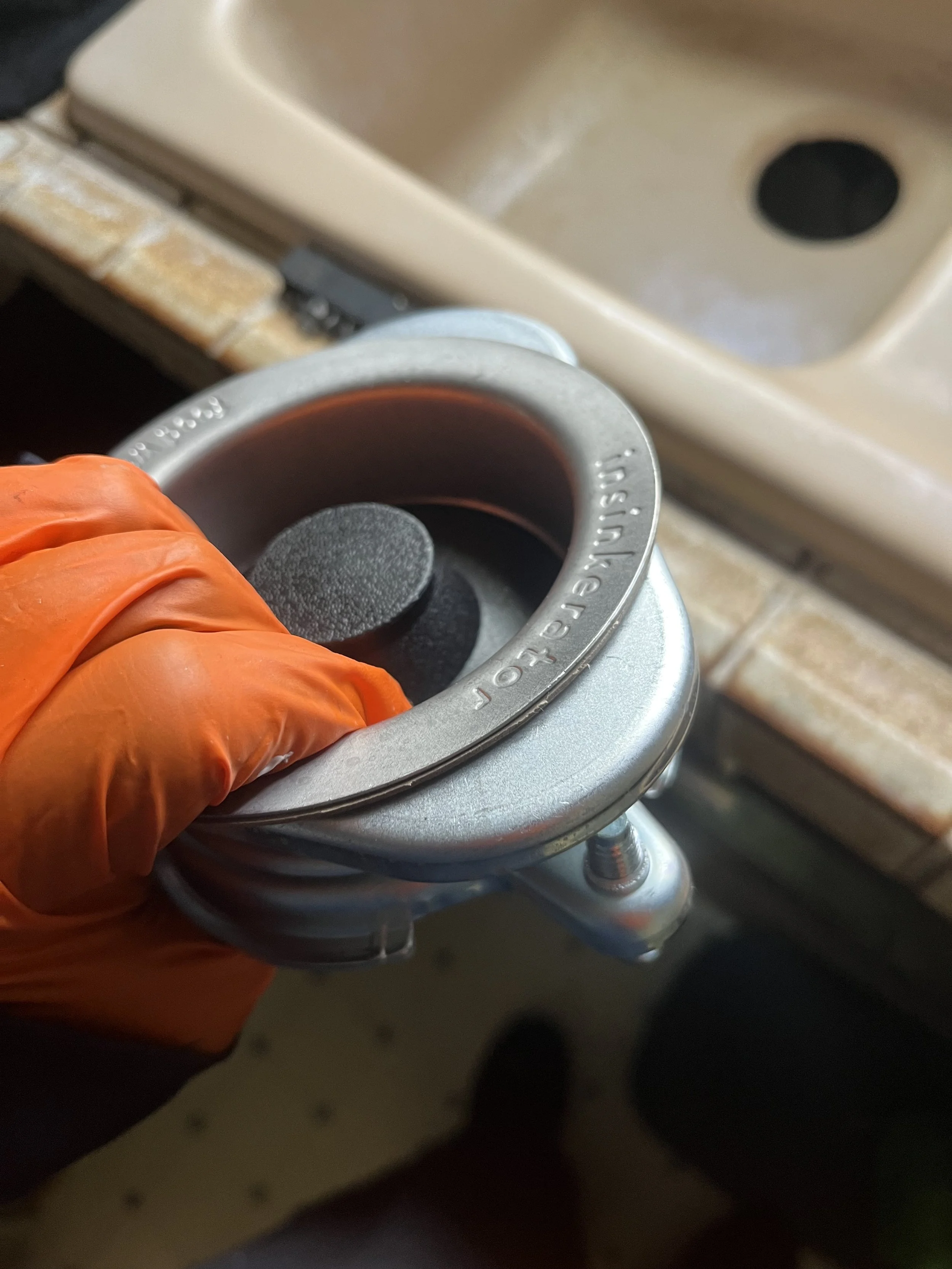 hand of a plumber repairing a kitchen sink basket strainer