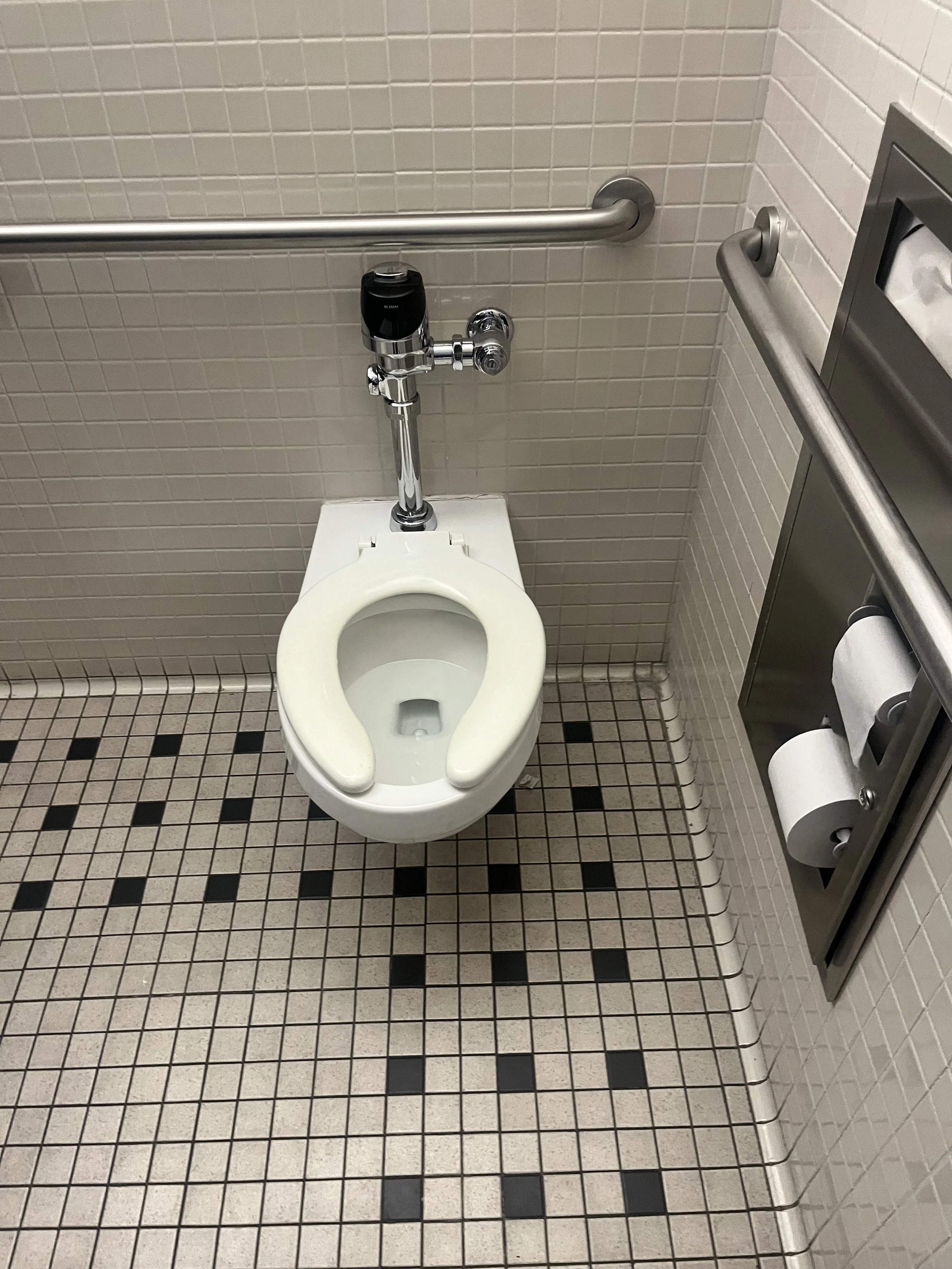 Public restroom with a wheelchair-accessible toilet, grab bars on the wall
