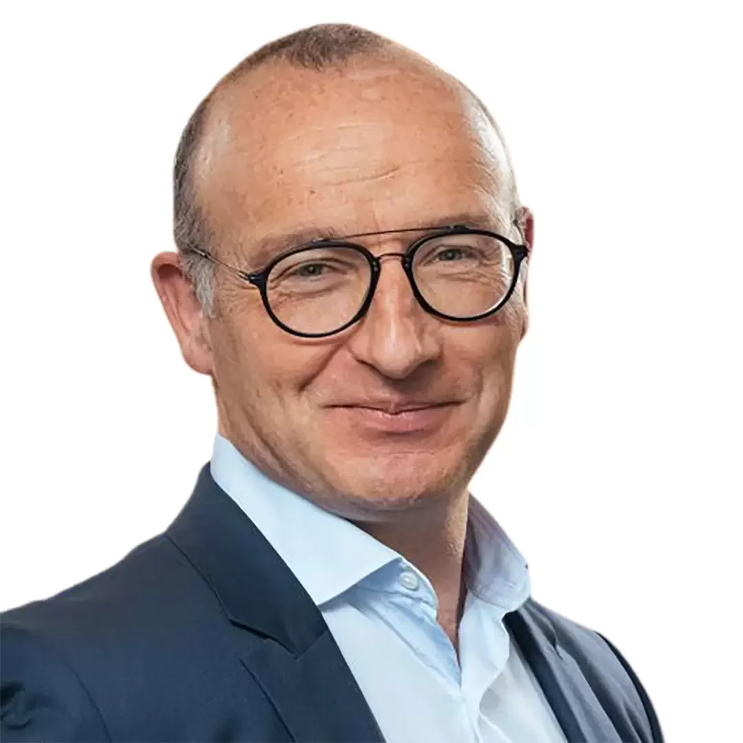 A smiling man with a receding hairline, wearing glasses, a white shirt, and a dark suit against a white background.