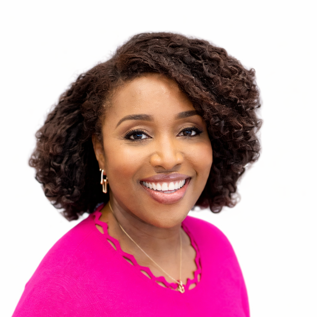 A woman with medium brown skin, curly voluminous hair, and a bright smile, wearing a pink top with cutout details around the neckline and gold jewelry, against a white background.
