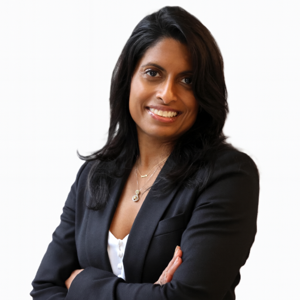 Professional woman with black hair wearing a black blazer and white blouse, smiling with arms crossed against a white background.