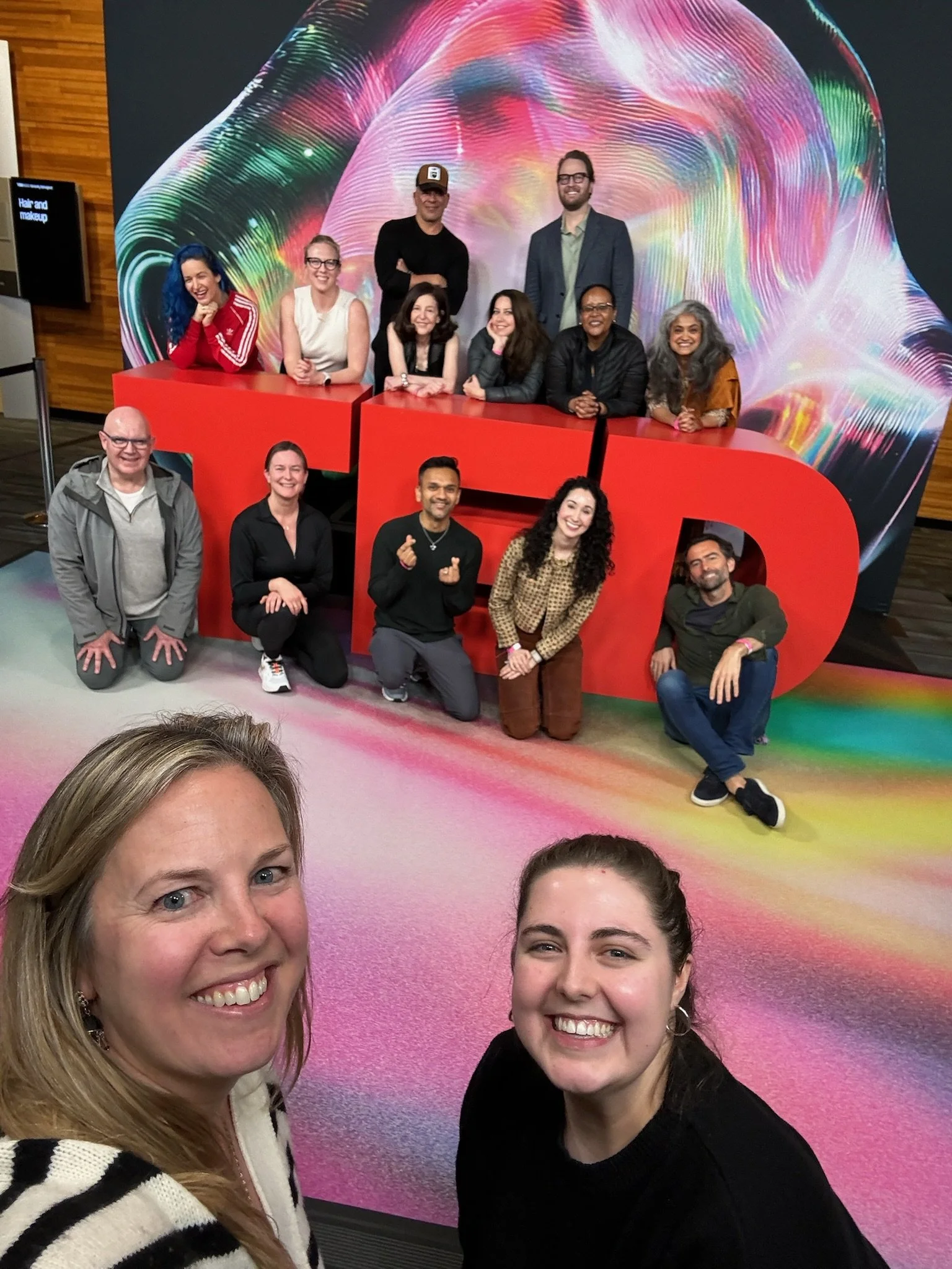 Nicole Darsney with a group of people posing in front of the large TED logo at the TED Conference.